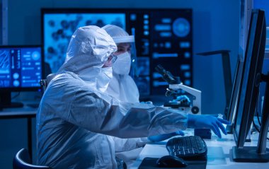 Profesyonel bilim adamları modern bir bilimsel araştırma laboratuvarında bir aşı üzerinde çalışıyorlar. Genetik mühendisliği işyeri. Gelecekteki teknoloji ve bilim konsepti.