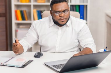 Ev ofisinde serbest tasarımcı işyeri. Genç Afro-Amerikalı bir adam bilgisayar, grafik tableti ve diğer cihazları kullanıyor. Uzak görev.