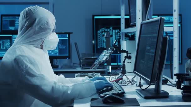 Microelectronics engineer works in a modern scientific laboratory on computing systems and microprocessors. Electronic factory worker is testing the motherboard and coding the firmware. — Stock Video