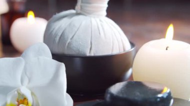 Spa arka planı. Havlu, mumlar, çiçekler, masaj taşları ve bitkisel toplar. Masaj, oryantal terapi, refah ve meditasyon.