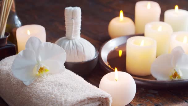 Спа фон. Рушник, свічки, квіти, камені для масажу та трав'яні кульки. Масаж, східна терапія, благополуччя та медитація . — стокове відео