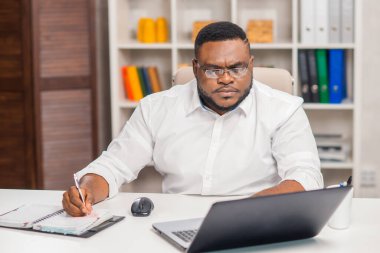 Ev ofisinde serbest tasarımcı işyeri. Genç Afro-Amerikalı bir adam bilgisayar, grafik tableti ve diğer cihazları kullanıyor. Uzak görev.