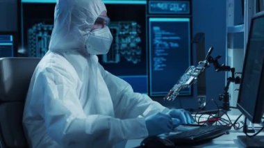 Mikro elektronik mühendisi, bilgisayar sistemleri ve mikroişlemciler üzerine modern bir bilim laboratuvarında çalışıyor. Elektronik fabrika işçisi ana kartı test ediyor ve yazılımı kodluyor..