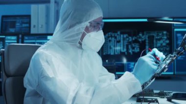 Mikro elektronik mühendisi, bilgisayar sistemleri ve mikroişlemciler üzerine modern bir bilim laboratuvarında çalışıyor. Elektronik fabrika işçisi ana kartı test ediyor ve yazılımı kodluyor..