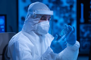 Koruyucu kıyafetli doktor modern bir laboratuvarda bilimsel deneyler yapıyor ve aşı geliştiriyor. Genetik mühendisliği işyeri. Bilim ve tıp kavramı.