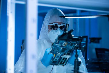 Mikro elektronik mühendisi, bilgisayar sistemleri ve mikroişlemciler üzerine modern bir bilim laboratuvarında çalışıyor. Elektronik fabrika işçisi ana kartı test ediyor ve yazılımı kodluyor..