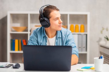 Serbest çalışanların ya da ev ofisinin iş yeri. Genç adam bilgisayar ve diğer cihazları kullanarak çalışır. Uzak görev.