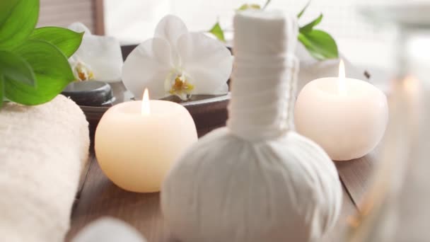 Fondo del spa. Toalla, velas, flores, piedras masajeadoras y bolas de hierbas. Masaje, terapia oriental, bienestar y meditación. — Vídeo de stock