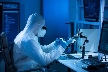 Mikro elektronik mühendisi, bilgisayar sistemleri ve mikroişlemciler üzerine modern bir bilim laboratuvarında çalışıyor. Elektronik fabrika işçisi ana kartı test ediyor ve yazılımı kodluyor..