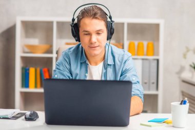 Serbest çalışanların ya da ev ofisinin iş yeri. Genç adam bilgisayar ve diğer cihazları kullanarak çalışır. Uzak görev.