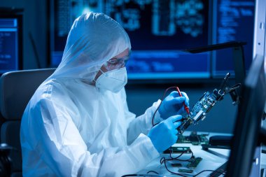 Mikro elektronik mühendisi, bilgisayar sistemleri ve mikroişlemciler üzerine modern bir bilim laboratuvarında çalışıyor. Elektronik fabrika işçisi ana kartı test ediyor ve yazılımı kodluyor..