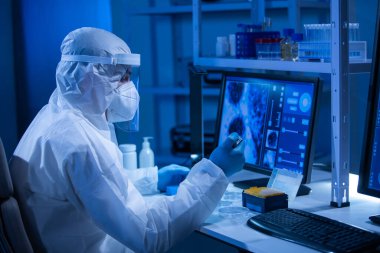 Koruyucu kıyafetli doktor modern bir laboratuvarda bilimsel deneyler yapıyor ve aşı geliştiriyor. Genetik mühendisliği işyeri. Bilim ve tıp kavramı.