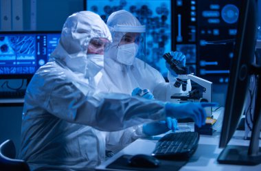 Profesyonel bilim adamları modern bir bilimsel araştırma laboratuvarında bir aşı üzerinde çalışıyorlar. Genetik mühendisliği işyeri. Gelecekteki teknoloji ve bilim konsepti.