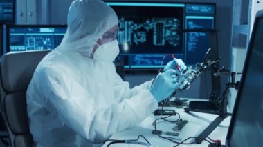 Mikro elektronik mühendisi, bilgisayar sistemleri ve mikroişlemciler üzerine modern bir bilim laboratuvarında çalışıyor. Elektronik fabrika işçisi ana kartı test ediyor ve yazılımı kodluyor..