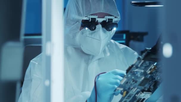Ingegnere di microelettronica lavora in un moderno laboratorio scientifico su sistemi informatici e microprocessori. Il lavoratore elettronico della fabbrica sta testando la scheda madre e codificando il firmware. — Video Stock