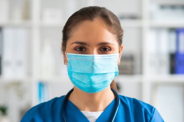 Hastane ofisinde çalışan profesyonel tıp doktoru koruyucu maskeli genç ve çekici kadın doktorların portresi..