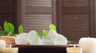 Spa arka planı. Havlu, mumlar, çiçekler, masaj taşları ve bitkisel toplar. Masaj, oryantal terapi, refah ve meditasyon.