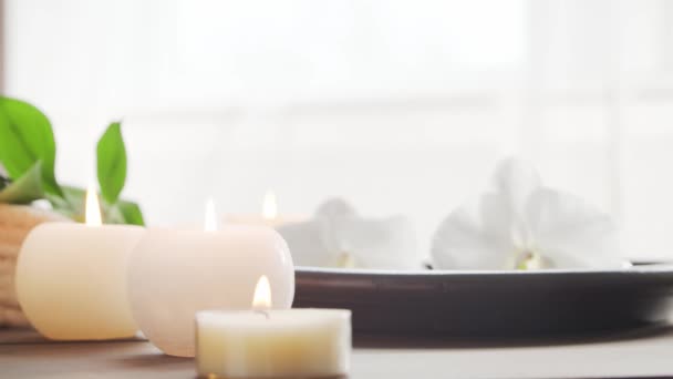 Fondo del spa. Toalla, velas, flores, piedras masajeadoras y bolas de hierbas. Masaje, terapia oriental, bienestar y meditación. — Vídeo de stock