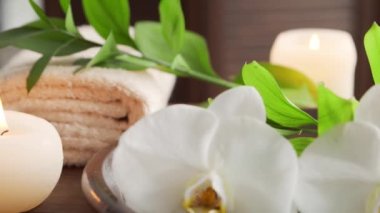 Spa arka planı. Havlu, mumlar, çiçekler, masaj taşları ve bitkisel toplar. Masaj, oryantal terapi, refah ve meditasyon.
