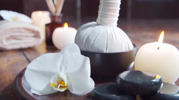 Fondo del spa. Toalla, velas, flores, piedras masajeadoras y bolas de hierbas. Masaje, terapia oriental, bienestar y meditación. — Vídeo de stock