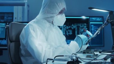 Mikro elektronik mühendisi, bilgisayar sistemleri ve mikroişlemciler üzerine modern bir bilim laboratuvarında çalışıyor. Elektronik fabrika işçisi ana kartı test ediyor ve yazılımı kodluyor..