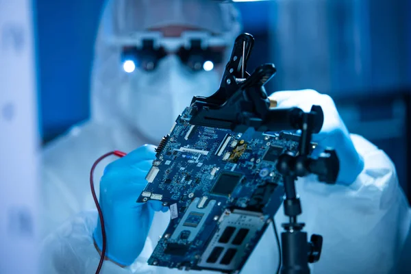 Ingeniero de Microelectrónica trabaja en un moderno laboratorio científico sobre sistemas informáticos y microprocesadores. El trabajador electrónico de la fábrica está probando la placa base y codificando el firmware. — Foto de Stock