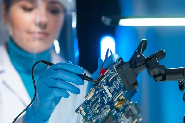 Female microelectronics engineer works in a scientific laboratory on computing systems and microprocessors. Professional electronic factory worker is testing the motherboard and coding the firmware. — Stock Photo, Image