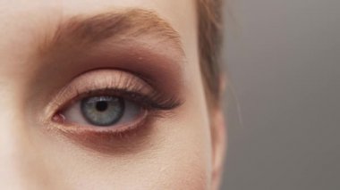 Gri arka planda genç, güzel ve doğal bir kadının stüdyo portresi. Yüz gerdirme, makyaj ve makyaj malzemeleri..