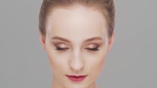 Studio portret van jonge, mooie en natuurlijke vrouw op grijze achtergrond. Gezichtsheffen, cosmetica en make-up. — Stockvideo