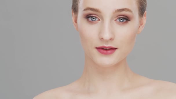 Studio porträtt av ung, vacker och naturlig kvinna över grå bakgrund. Ansiktslyftning, kosmetika och make-up. — Stockvideo