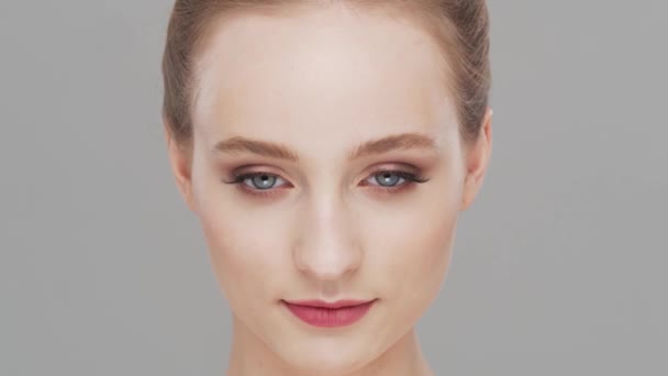 Retrato de estudio de mujer joven, hermosa y natural sobre fondo gris. Levantamiento facial, cosméticos y maquillaje. — Vídeos de Stock