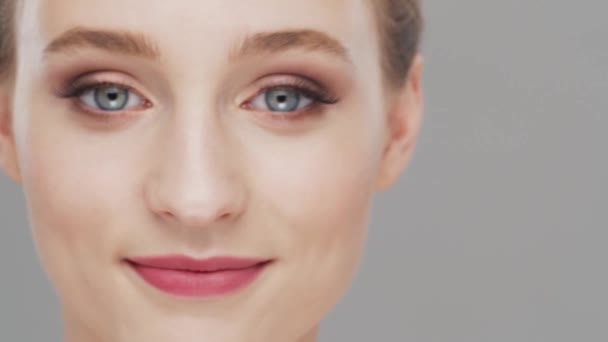 Studio porträtt av ung, vacker och naturlig kvinna över grå bakgrund. Ansiktslyftning, kosmetika och make-up. — Stockvideo