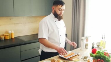 Genç, modern bir mutfakta gazlı somon balığı pişiriyor. Adam evde yemek hazırlıyor. Sağlıklı yemek pişirmek..