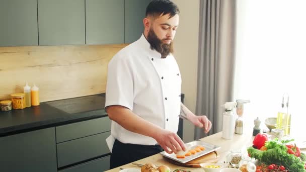Genç, modern bir mutfakta gazlı somon balığı pişiriyor. Adam evde yemek hazırlıyor. Sağlıklı yemek pişirmek.. — Stok video