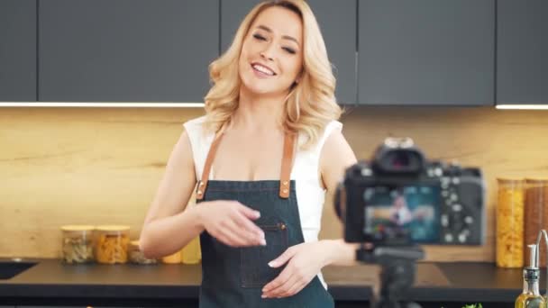 Une jeune femme prépare à manger et anime un spectacle culinaire. Le blogueur sort de la cuisine. Préparation végétarienne saine des aliments. — Video