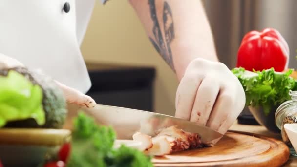 El joven chef está cortando pulpo en una cocina moderna. El hombre prepara comida en casa. Cocinar alimentos saludables. — Vídeos de Stock