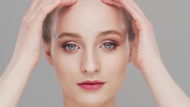 Retrato de estudio de mujer joven, hermosa y natural sobre fondo gris. Levantamiento facial, cosméticos y maquillaje. — Vídeo de stock