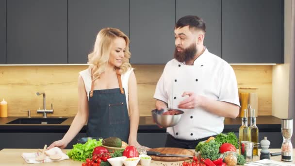 Mujer joven y hombre preparan comida y organizan un programa de cocina. Los bloggers fluyen desde la cocina. Preparación de alimentos saludables. — Vídeos de Stock