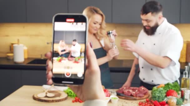 Mujer joven y hombre preparan comida y organizan un programa de cocina. Los bloggers fluyen desde la cocina. Preparación de alimentos saludables. — Vídeos de Stock