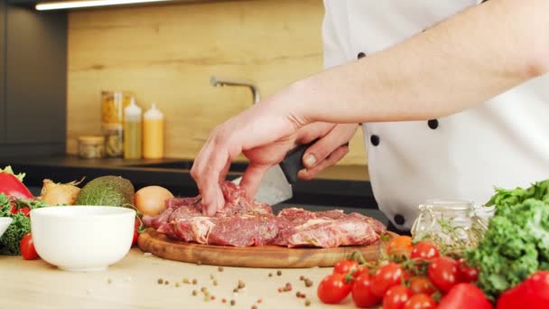 De jonge chef snijdt vlees in een moderne keuken. De man bereidt thuis eten. Gezond voedsel koken. — Stockvideo
