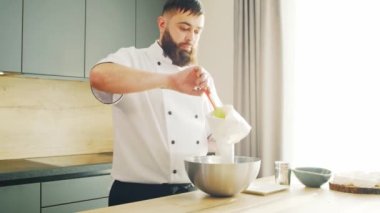 Young modern bir mutfakta kremalı tatlı hazırlıyor. Adam evde yemek hazırlıyor. Sağlıklı yemek pişirmek..