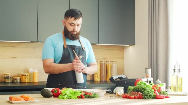 Genç aşçı modern bir mutfakta somon balığını gaz ocağıyla kızartıyor. Adam evde yemek hazırlıyor. Sağlıklı yemek pişirmek.. — Stok video