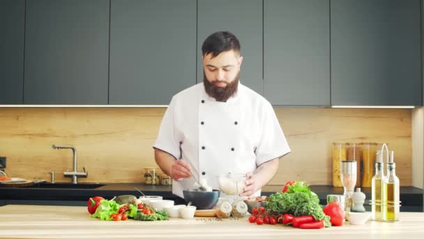 Young bereidt een porseleinen kom in een moderne keuken. De man bereidt thuis eten. Gezond voedsel koken. — Stockvideo