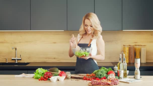 Mujer joven prepara la comida y organiza un espectáculo de cocina. El blogger fluye desde la cocina. Preparación vegetariana de alimentos saludables. — Vídeos de Stock