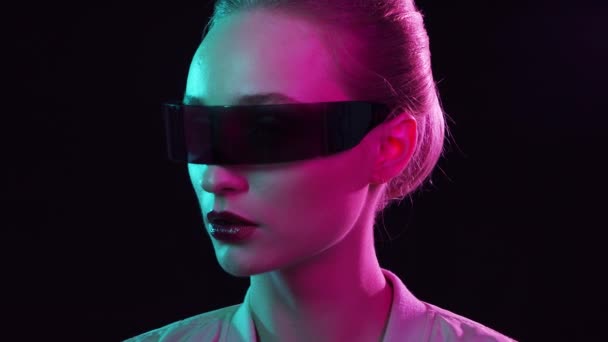 Portrait d'adolescente dans le style cyberpunk. Jeune femme posant dans des lunettes de soleil futuristes. Studio créatif lumière. — Video