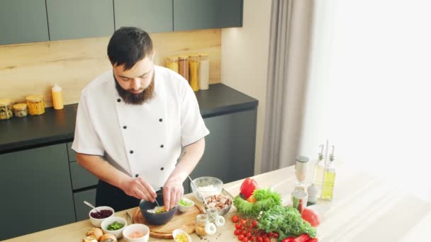 Young bereidt een porseleinen kom in een moderne keuken. De man bereidt thuis eten. Gezond voedsel koken. — Stockvideo