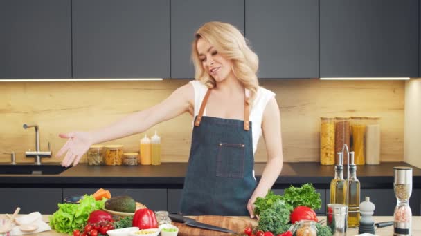 Mujer joven prepara la comida y organiza un espectáculo de cocina. El blogger fluye desde la cocina. Preparación vegetariana de alimentos saludables. — Vídeos de Stock