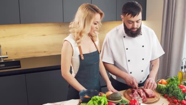 Mujer joven y hombre preparan comida y organizan un programa de cocina. Los bloggers fluyen desde la cocina. Preparación de alimentos saludables. — Vídeos de Stock