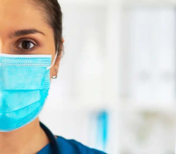 Berufsärztin im Krankenhausbüro, Porträt einer jungen und attraktiven Ärztin mit Schutzmaske. — Stockfoto