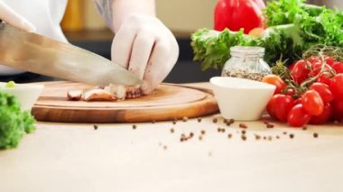 Genç aşçı modern bir mutfakta ahtapot kesiyor. Adam evde yemek hazırlıyor. Sağlıklı yemek pişirmek..